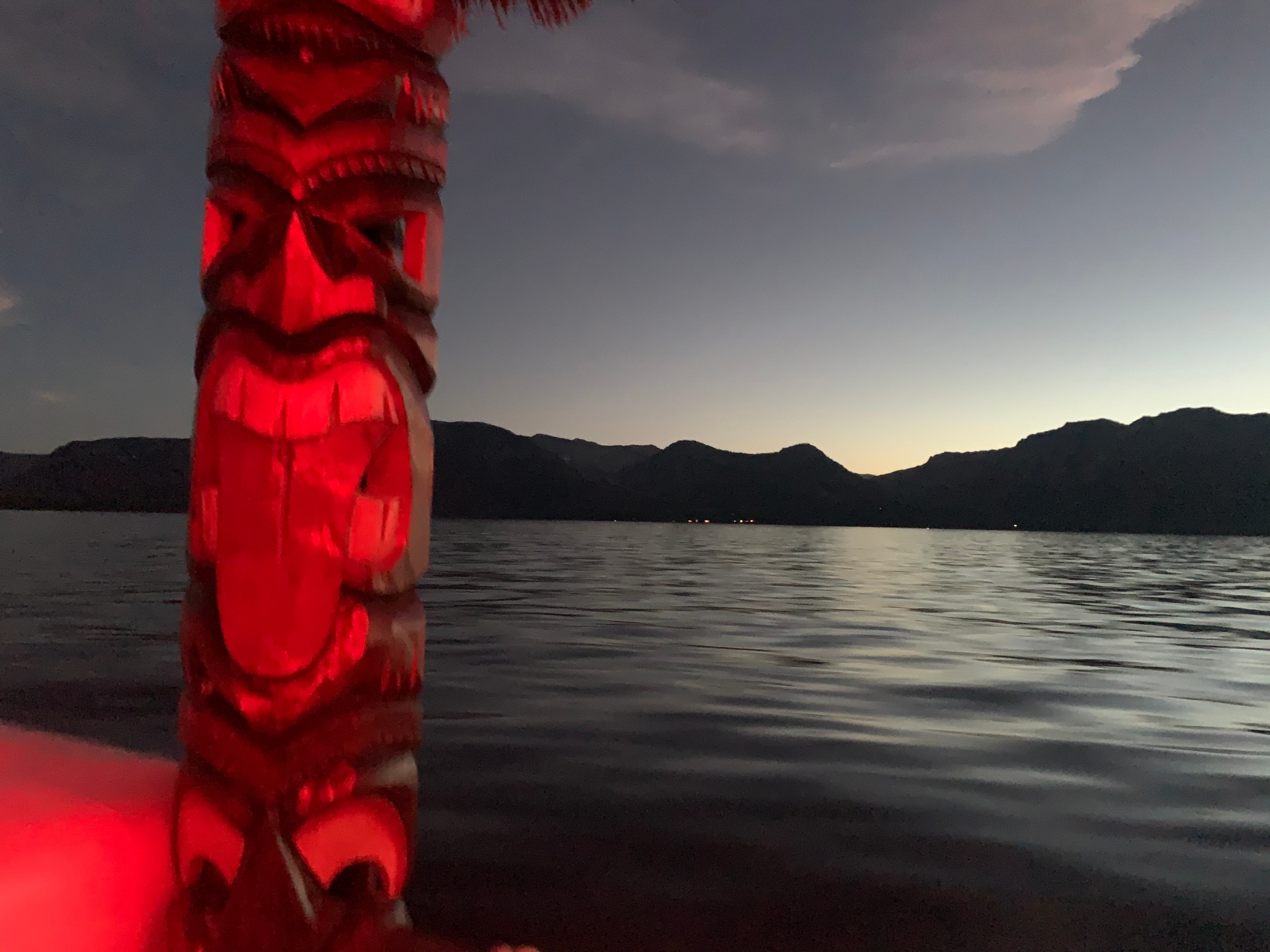Tiki totem lit red at dusk over a calm Tahoe shoreline
